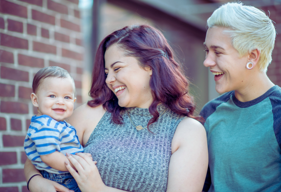 Two women holding a baby and smiling