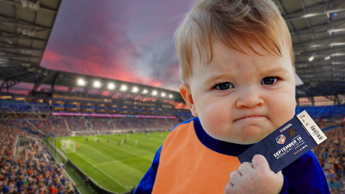 A baby clutching a soccer game ticket